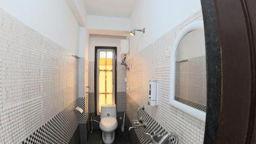 a white bathroom with a toilet and a mirror at Nini's Homestay, Kalimpong in Pedong