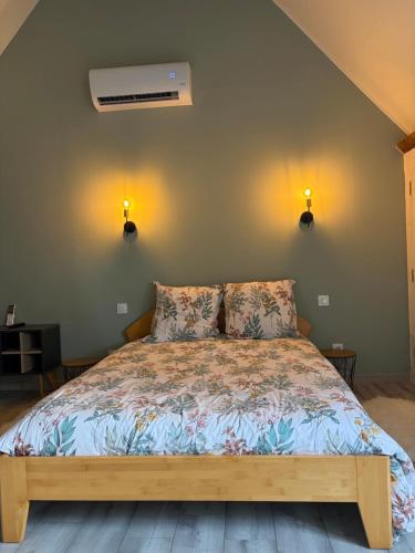 a bed in a bedroom with two lights on the wall at Gîte des Tilleuls - Nature, calme, télétravail - Animaux acceptés in Graçay