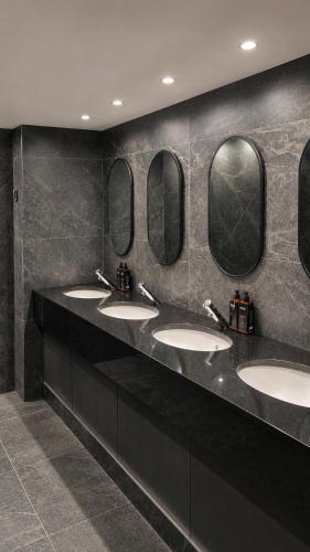 a row of sinks in a bathroom with four mirrors at Arnolds Hotel in Dunfanaghy