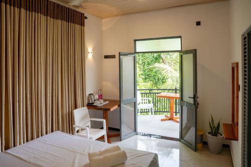 a bedroom with a bed and a desk and a balcony at JAMI River Side Hotel & Yala Safari Place in Tissamaharama