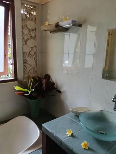 a bathroom with a sink and a toilet with flowers on the counter at Sang Fajar Ubud in Ubud