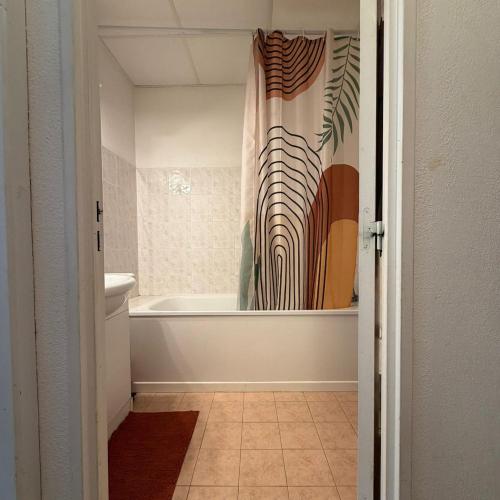a bathroom with a tub and a shower curtain at Appartement La Parenthèse Verte - Capvern in Capvern