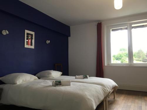 two beds in a bedroom with a blue wall at La maison des ponts in Pont-sur-Madon