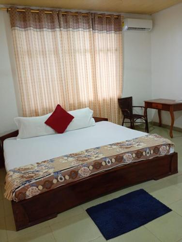 a bedroom with a large bed with a red pillow at Abuesi Beach Resort in Sekondi-Takoradi