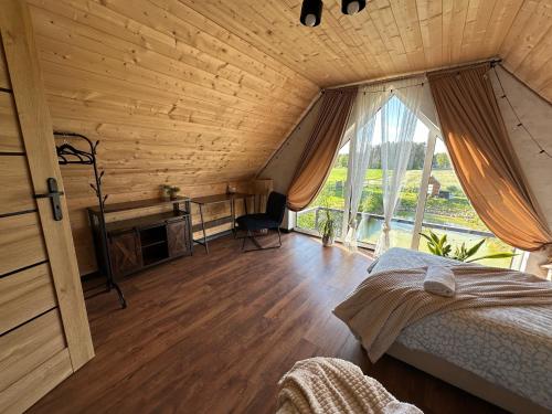 a bedroom with a bed and a desk and a window at Hulaj Dusza - dom nad stawem in Cisów