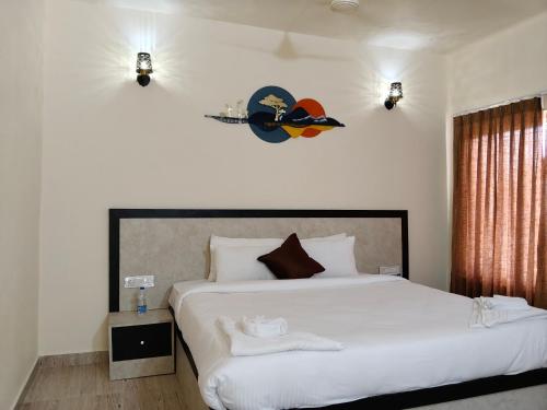 a bedroom with a large bed with white sheets at Tutti Cafe in Hampi