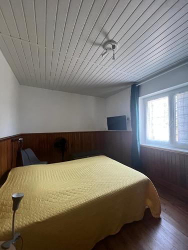 a bedroom with a yellow bed and a window at Logement avec parking max 7 personnes in Eauze