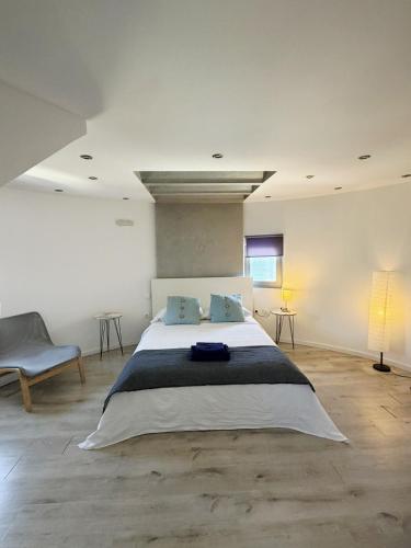 a bedroom with a large bed and a chair at Anemos Mill House in Imerovigli