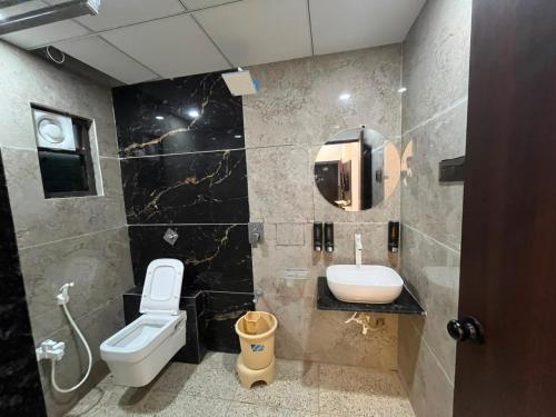 a bathroom with a toilet and a sink and a mirror at Hotel Shree Kesari Nandan in Dwarka