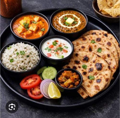 a black plate of food with rice and a pizza at Alwar stay in Alwar