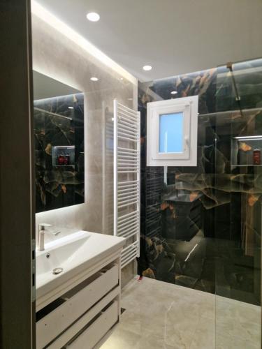 a bathroom with a sink and a shower with a mirror at Alykes Maisonette Prv Jacuzzi in Kontokali