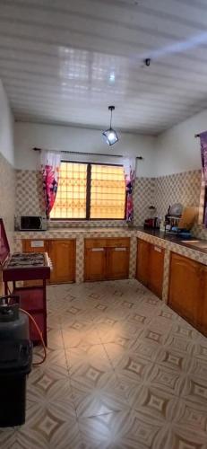 a large room with a kitchen with two windows at Furyan Lodge in Cape Coast