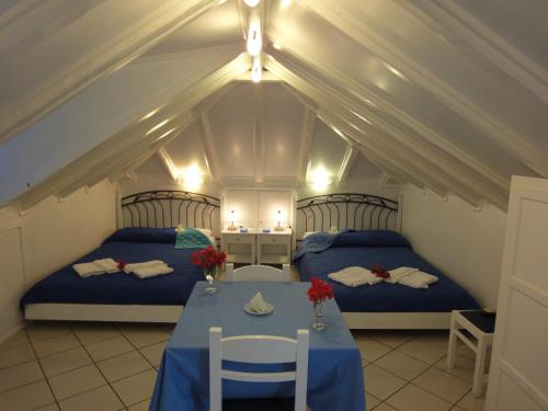 um quarto com duas camas e uma mesa num sótão em Botsis Guest House em Hydra