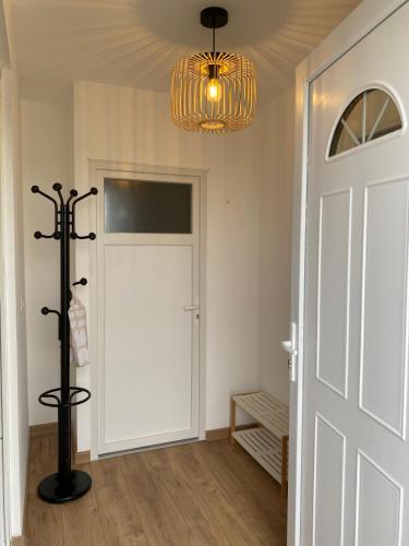a hallway with a white door and a chandelier at Maison Pro Le Blanc - 3 chambres plus un canapé lit in Le Blanc