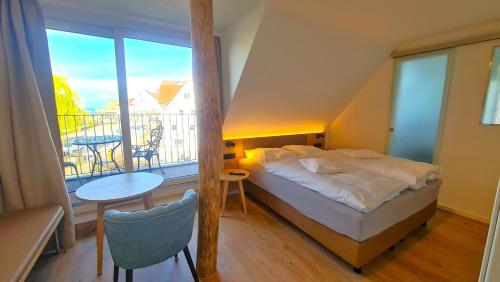 a bedroom with a bed and a balcony with a table at Gästehaus Seeblick in Langenargen