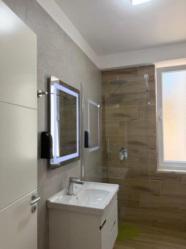 a bathroom with a sink and a mirror and a shower at CoastAL Hotel Shengjin in Shëngjin