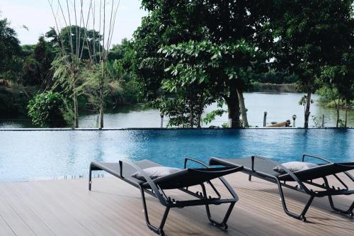 two chairs sitting on a deck near a swimming pool at Riverawan Hotel in Chanthaburi