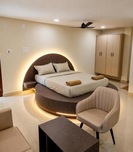 a bedroom with a large bed and a chair at Maruthi inn hotel in Vijayawāda