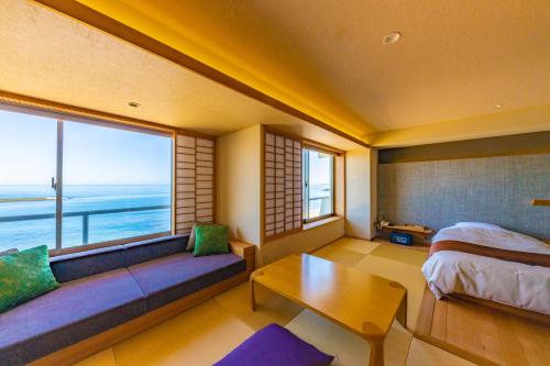 a bedroom with a couch and a bed and a window at Kaike Grand Hotel Tensui in Yonago