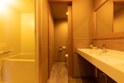 a bathroom with a sink and a tub and a toilet at Kaike Grand Hotel Tensui in Yonago