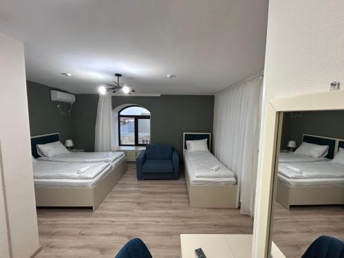 a room with two beds and a blue chair at HIQ Hotel Home Inn Qusar in Qusar