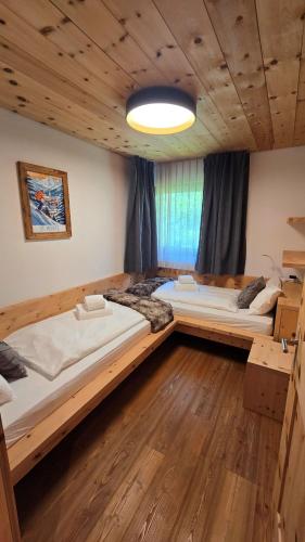 two beds in a room with wooden floors at Splendida e soliva dimora con giardino in La Punt-Chamues-ch