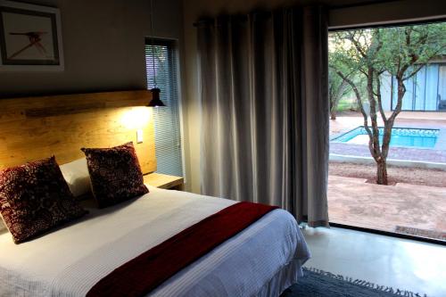 a bedroom with a bed and a large window at Switsongo Boutique B&B in Hoedspruit