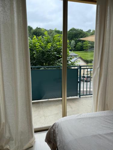a bedroom with a window looking out at a balcony at Appartement La Parenthèse Verte - Capvern in Capvern