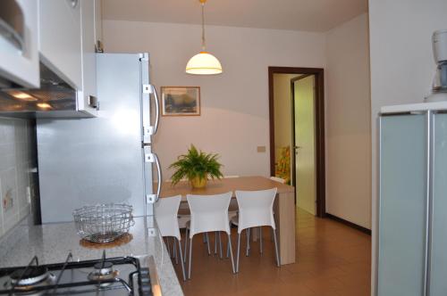 een keuken met een tafel en witte stoelen bij Villaggio Dei Fiori in Bibione