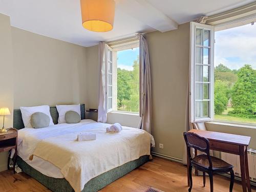 a bedroom with a bed and a desk and two windows at Clos de Gauville in Brétigny
