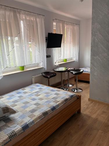 a bedroom with a bed and a table and two stools at Noclegi i Restauracja Gracja in Bełchatów