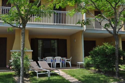 un patio con sedie e tavoli di fronte a un edificio di Villaggio Dei Fiori a Bibione