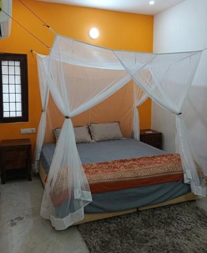 a bedroom with a bed with a mosquito net at Charming Stone Cottage in erstwhile grape gardens in Secunderabad