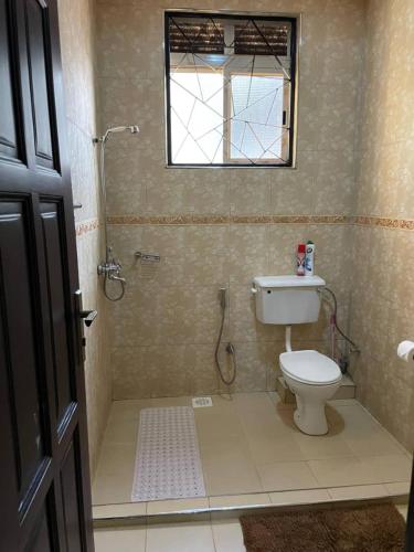 a bathroom with a toilet and a shower and a window at Mukisa Apartments in Kampala