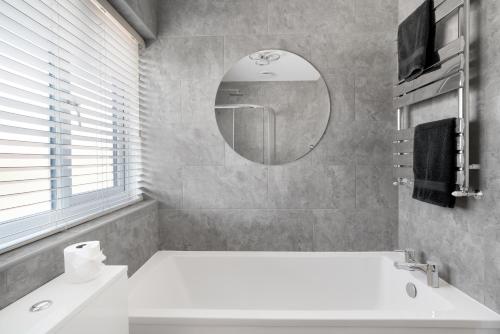 a bathroom with a white tub and a mirror at Perfect Getaway 1 in Middlesbrough