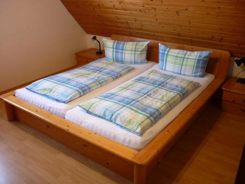 a wooden bed with two pillows on it at Weingut Bernhard in Daisendorf