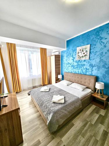 a bedroom with a large bed with a blue wall at Summerland Seaview Premium Apartments in Mamaia