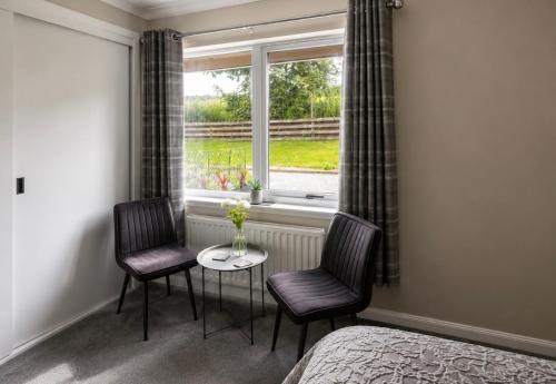 a bedroom with two chairs and a table and a window at Eldon Lea in Strathpeffer