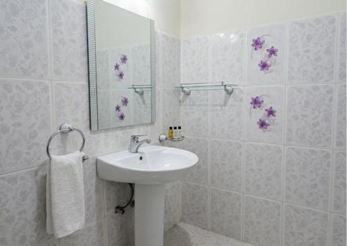a white bathroom with a sink and a mirror at Nilakma Lagoon in Negombo