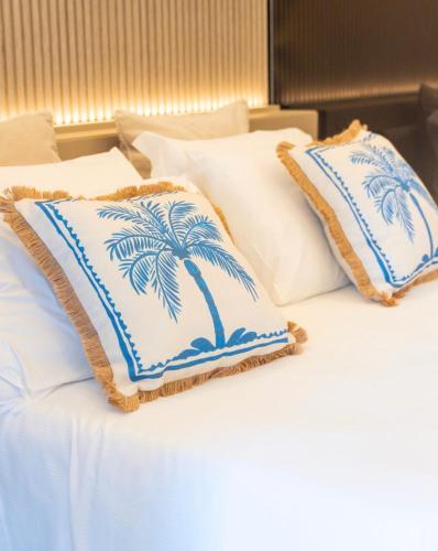 a bed with white pillows with a palm tree on it at Al Capri Suite & Private Pool in Capri