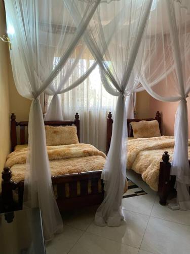 a bedroom with two beds with curtains and a window at Mukisa Apartments in Kampala