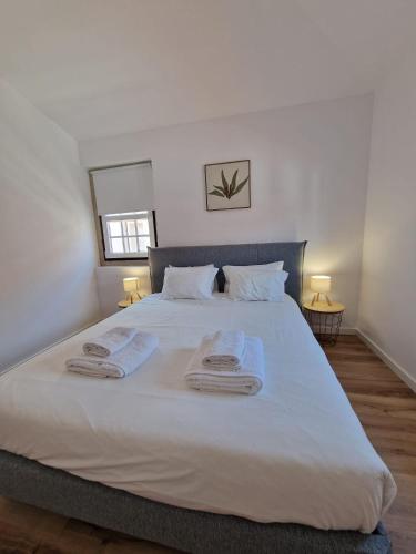 a bedroom with a large white bed with towels on it at Casa da Villa in Monção
