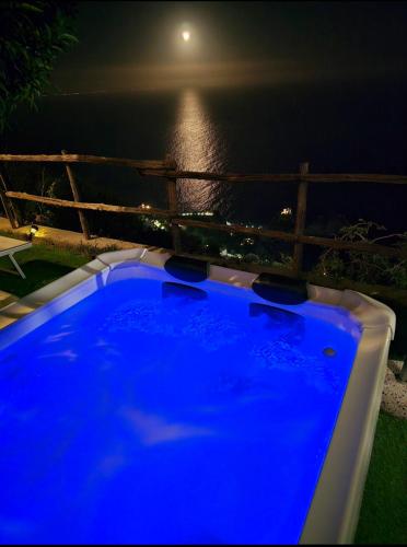 a blue hot tub with a view of the ocean at night at Solecore Amalficoast in Conca dei Marini