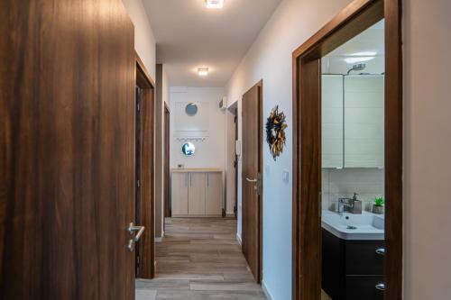 a hallway with a bathroom with a sink and a mirror at AH-Corso Wellness Residence in Siófok