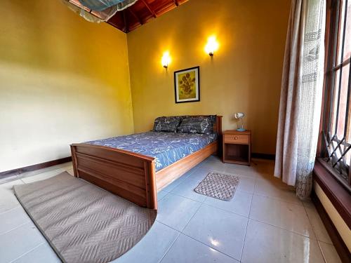 a bedroom with a bed in a yellow wall at Johannes Nest in Gampola