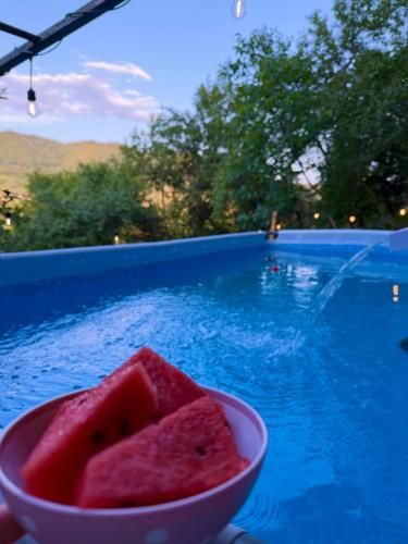 a bowl of watermelon sitting next to a swimming pool at Casa NIB Calimanesti in Călimăneşti