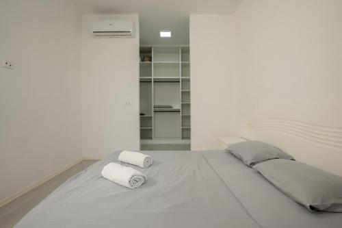 a white bedroom with two towels on a bed at MaisonNova Deluxe 2 in Tirana