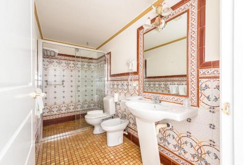 a bathroom with a sink and a toilet and a mirror at Hotel Noucentista in Sitges