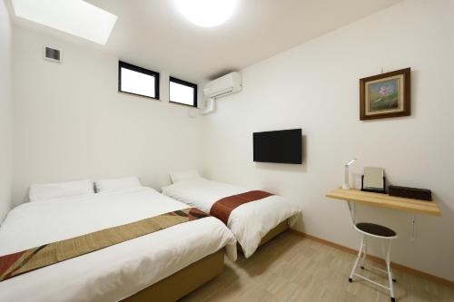 a bedroom with two beds and a desk with a computer at add-Hostel Uji Cha-gan-ju-tei in Uji