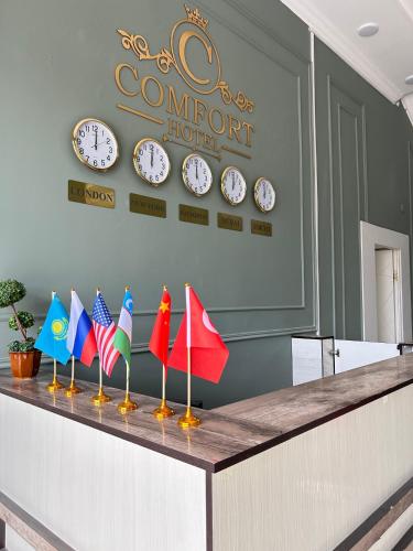 a row of flags on top of a counter with clocks at Comfort Hotel in Türkistan